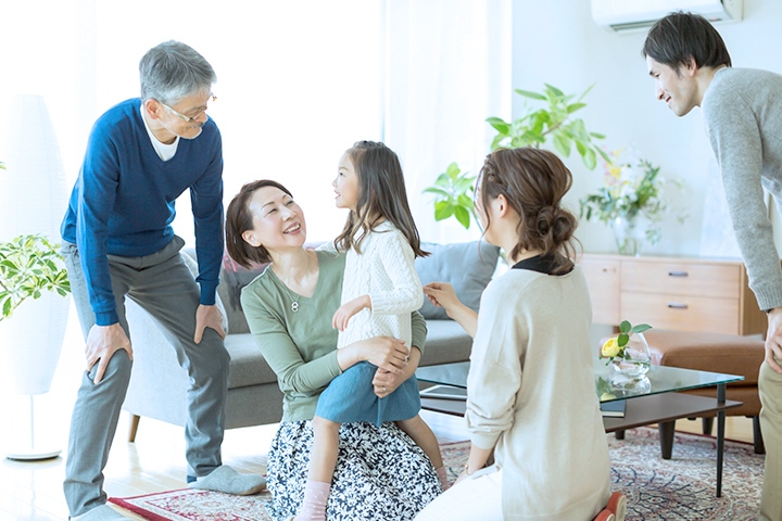 孫を抱き寄せる祖母とその家族の写真